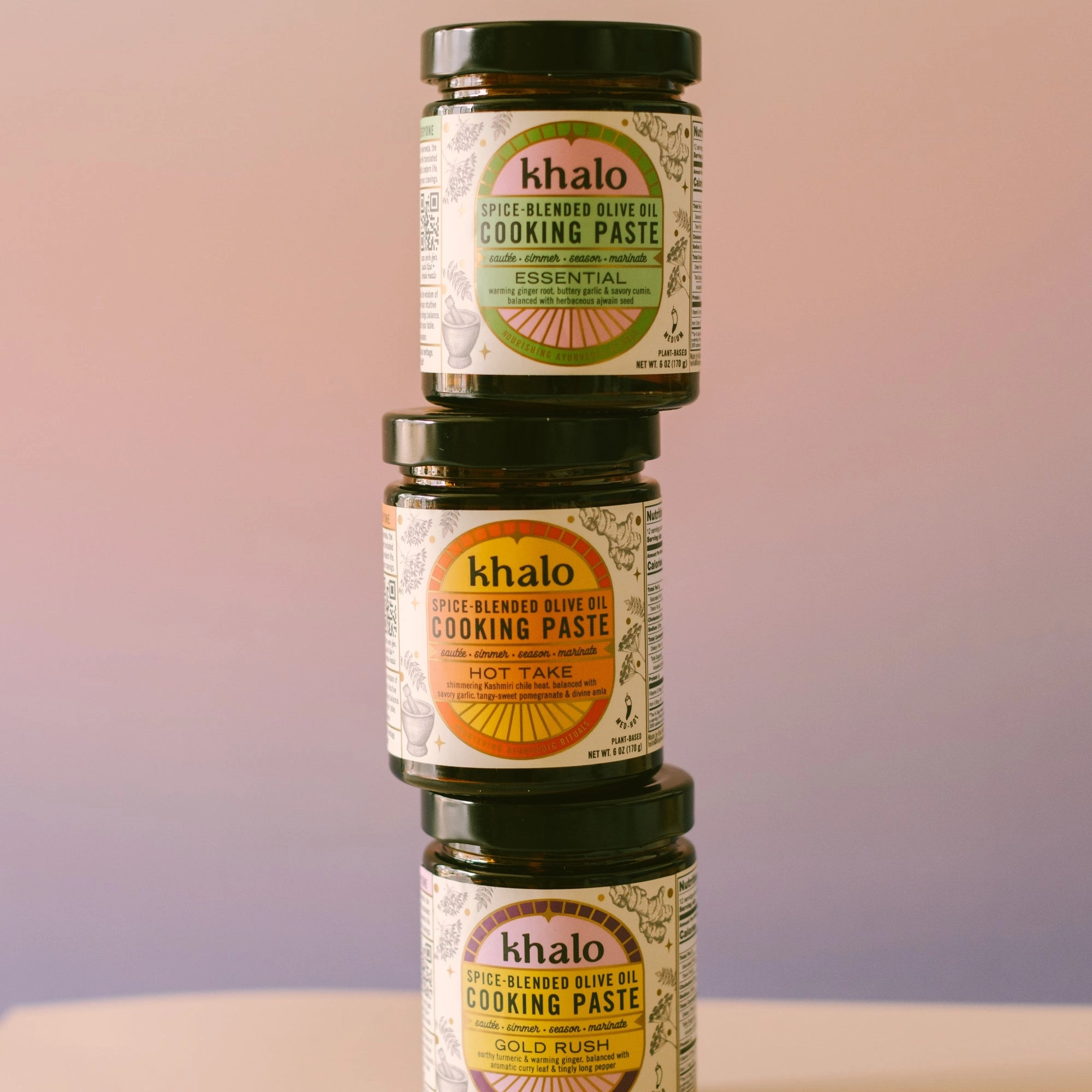 Three Khalo cooking paste jars stacked on a soft pink and lilac backdrop