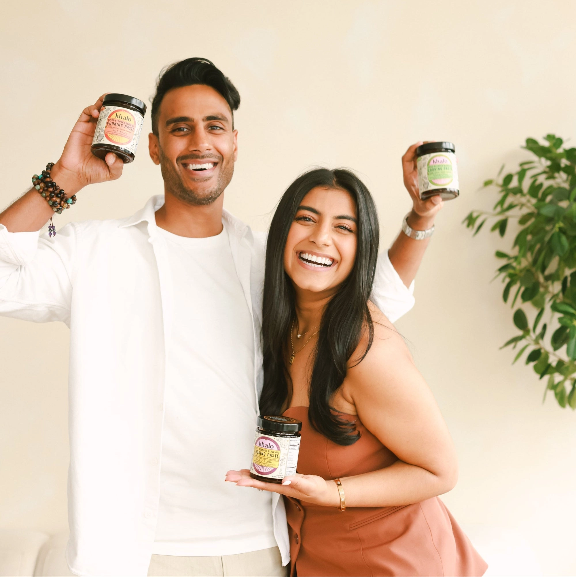 Two people smiling, each holding up a Khalo jar