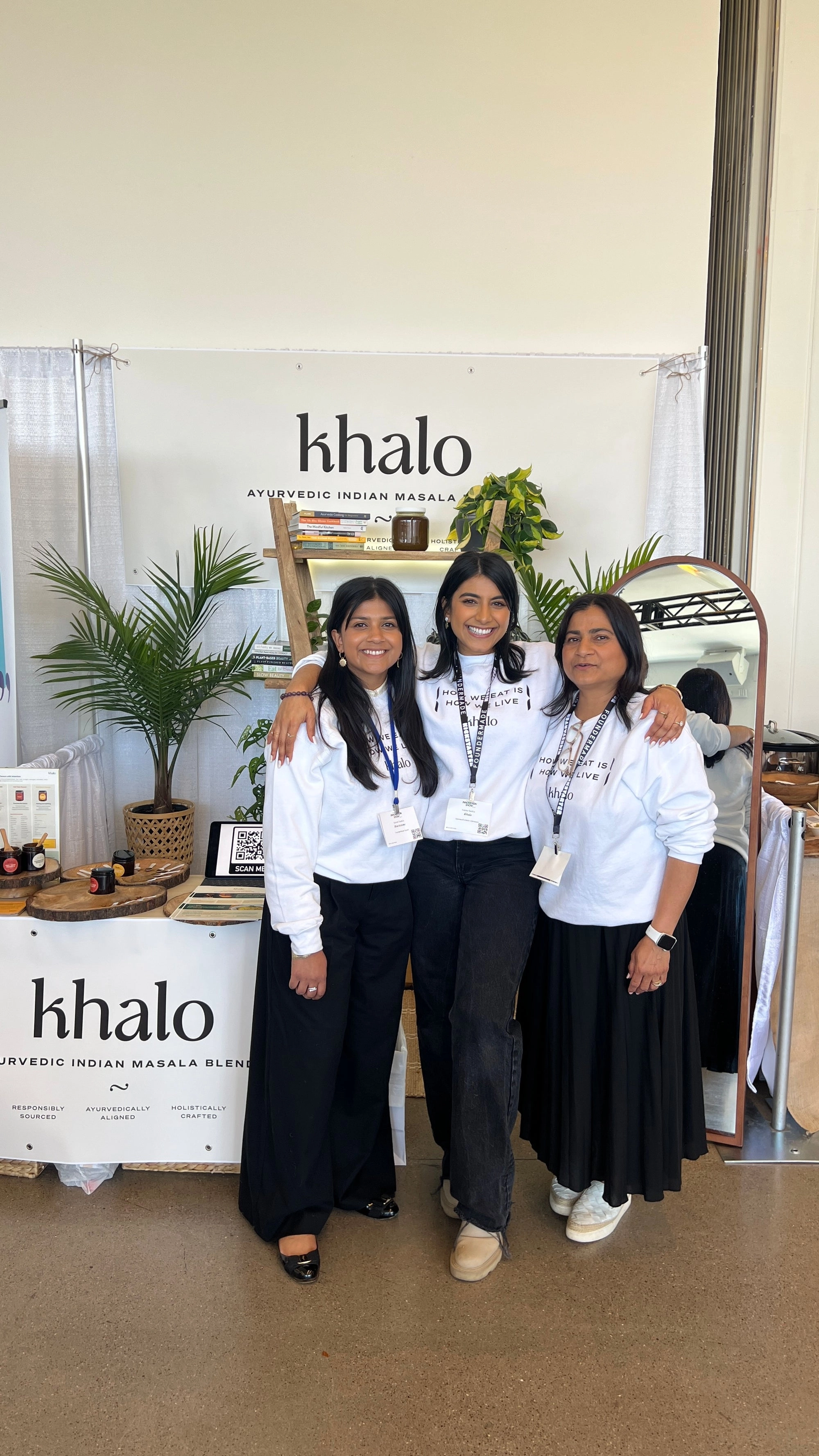 Four people in white shirts standing by a Khalo banner